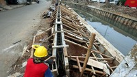 Pekerja tengah membuat grass block di tepi Kali Grogol.