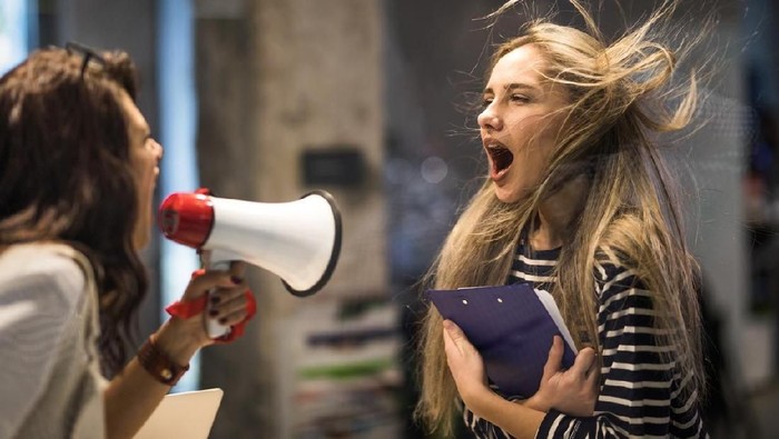 Ilustrasi emosi Rude female leader yelling at her coworker through megaphone.