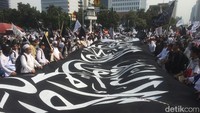 Foto: Massa menggabungkan bendera-bendera berukuran besar di Jalan Medan Merdeka Barat, Jakarta Pusat. (Rolando Fransiscus/detikcom)