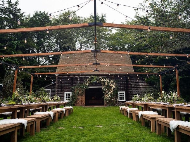 Rangkaian pesta pernikahan dimulai dengan rehearsel dinner yang digelar di halaman rumah komedian Jerry Seinfeld di Hamptons. Jamuan malam menggunakan meja dan bangku panjang yang terbuat dari kayu. Tidak ada tenda, hanya lampu-lampu yang bergelantungan yang menjadi atapnya. (Foto: Dok. Goop)