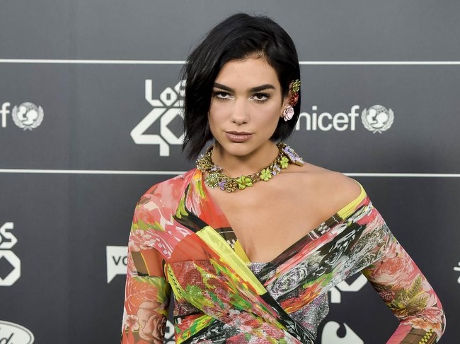 Dua Lipa menyempurnakan gayanya dengan statement nacklace bermotif floral dengan aksen neon. (Foto: Juan Naharro Gimenez/Getty Images)