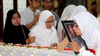 Sang istri mencium foto milik almarhum Dodi Junaidi saat tiba di Masjid Baitul Adli, kompleks Kejaksaan Agung, di Jakarta Selatan, Senin (5/11/2018).