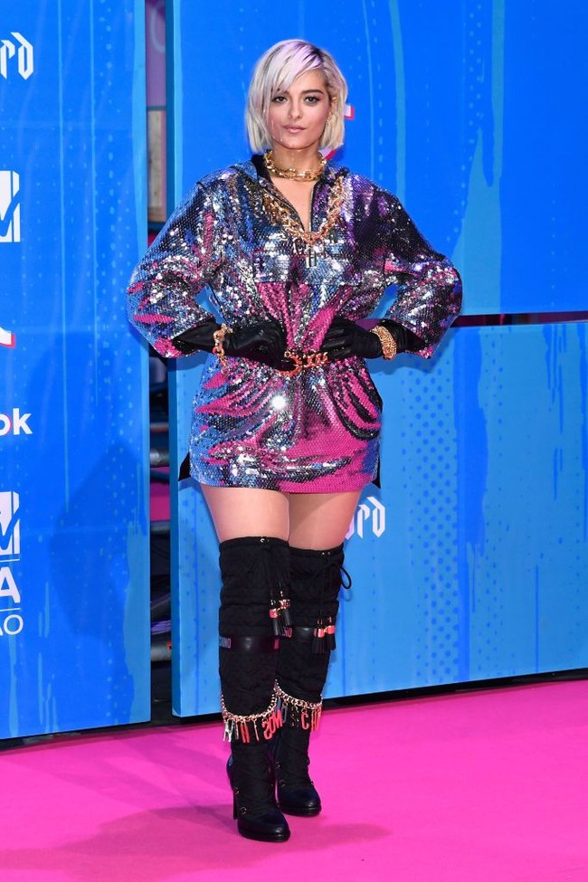 Gaun silver dengan hoodie, ikat pinggang statement, thigh high boots Moschino beraksen rantai membuat tampilan Bebe Rexha terlihat penuh. Tubuhnya juga tampak lebih pendek dengan padanan busana tersebut. Foto: Getty Images