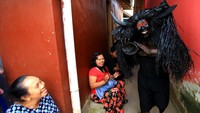 Salah seorang warga yang berdandan layaknya kerbau dengan tanduk buatan dan tubuh yang dilumuri cat berwarna hitam berjalan melintasi warga. 