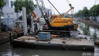 Pekerja menyelesaikan pembangunan turap di Sungai Ciliwung, Selasa (6/11/2018).