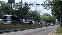 Para pengendara melintas di bawah alat ERP.