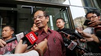 Mahfud tampak mengenakan kemeja merah lengan panjang.