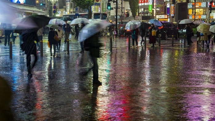 City in the Rain: Torrential downpour at rush hour in Tokyo street at night with people scurrying for shelter across wet pavement reflecting neon lights.