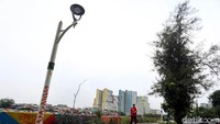 Seorang warga melintas di sekitar tiang lampu penerangan yang dikotori oleh coretan cat semprot.