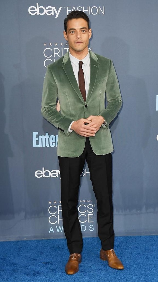 Rami memakai blazer hijau velvet yang meninggalkan kesan mewah. Dasi coklatnya disenadakan dengan sepatu kulitnya. (Foto: Getty Images)