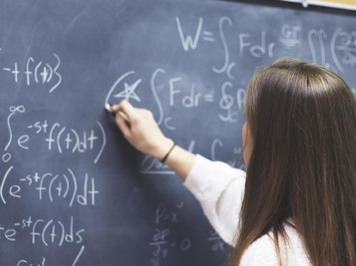 Female STEM student circling an important formula she wrote on the board.