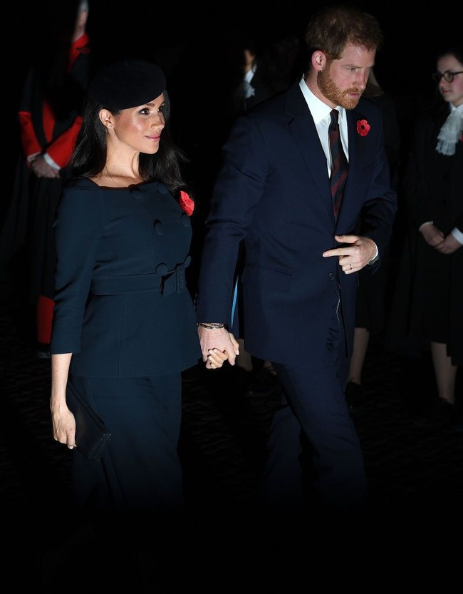 Meghan Markle yang sedang hamil mengenakan atasan peplum berwarna navy yang dipertegas dengan belt. Dia pun terlihat semakin cantik dengan rambut yang digerai saat digandeng oleh Pangeran Harry. Foto: Jack Taylor/Getty Images