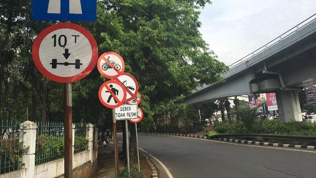 Rambu-rambu tersebut bersandingan dengan pohon yang cukup rindang.