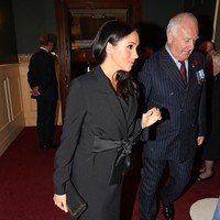 Meghan di lain sisi mengenakan coat dengan pita satin di pinggang yang menutupi perut hamilnya. Seperti Kate, clutch dan pump hitam pun jadi pilihan. Foto: Dok. Getty Images