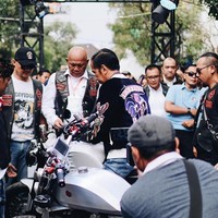 Ditengok di Instagram label tersebut, @rawtyperiot_co., jaket hitam keemasan model bomber ini terbuat dari bahan sutra silk dan velvet, dengan detail bordiran di bagian depan, lengan, dan belakang. Di bagian dada sebelah kiri terdapat tulisan Bur-Yam-Cer RTR. Sementara di bagian kirinya terdapat gambar roda dengan bendera racing (kotak-kotak hitam-putih). Di bagian belakangnya bertuliskan Bubur Ayam Racer, berikut gambar ayam. Sementara kedua lengan masing-masing dihiasi gambar ayam beserta roda yang berapi. (Foto: Instagram/@rawtype_riot)