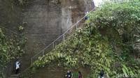 Untuk menuju ke air terjun, traveler harus menuruni anak tangga tembok di tebing yang cukup curam. Butuh kehati-hatian karena jalannya kecil dan licin. (Syanti/detikTravel)
