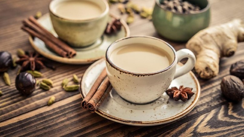 Wedang Traditional indian drink - masala chai tea (milk tea) with spices on wooden background