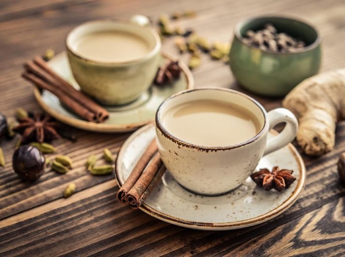 Traditional indian drink - masala chai tea (milk tea) with spices on wooden background