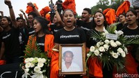 Para mahasiswa membawa foto dan karangan bunga dalam aksi tersebut.