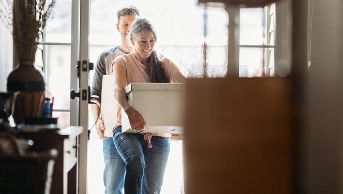 A couple in their 50s moves in to their new home, unpacking boxes and enjoying the time together.  Could also depict moving out of a home.