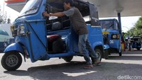 Seorang sopir mendorong bajajnya untuk maju ke antrean.