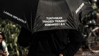 Payung yang mereka bawa bertuliskan tuntutan aksi.