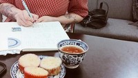 Begini sibuknya Claudia ketika tengah bekerja. Ditemani secangkir teh hangat, dan kue di meja kerjanya. Foto: Instagram @miss_adinda_mae