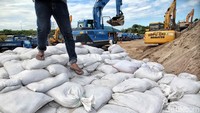 Sejumlah petugas Suku Dinas Daya Air Jakarta Utara sedang menata karung pasir di Gudang Material Ketel Uap, Ancol, Jakarta Utara.