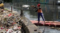 Petugas membersihkan sampah dari Kali Item.