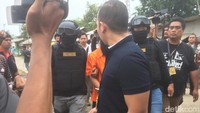 Haris kemudian turun dari mobil. Dia jalan kaki dan dikawal polisi yang menenteng senjara menuju lokasi pembuangan linggis yang dipakai untuk membunuh Daperum Nainggolan dan istrinya Maya Simamora. Foto: (Rolan-detikcom)