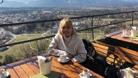 Di Salzburg, Austria, Felicia hangatkan badan dengan menyesap minuman hangat. Pemandangan gunung di belakangnya keren banget! Foto: Instagram feliciahutapeaaa