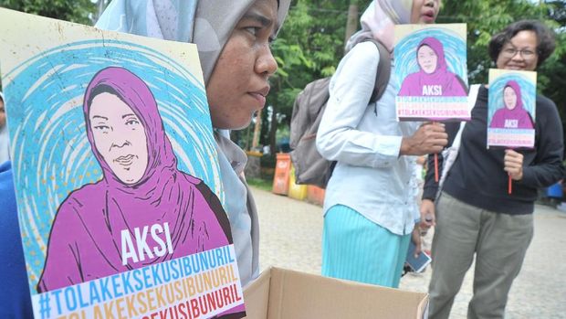 Peserta aksi menunjukkan poster dan kotak donasi pada aksi Tolak Eksekusi Baiq Nuril Maknun di Taman Kamabang Iwak Palembang, Minggu (18/11).