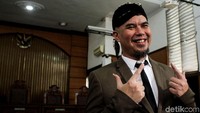 Ahmad Dhani berpose di depan kamera saat jalani sidang tuntuan soal cuitan ujaran kebencian.