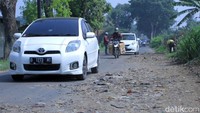 Sejumlah pengendara berusaha menghindari lubang yang telah ditambal dengan tanah bercampur sampah.