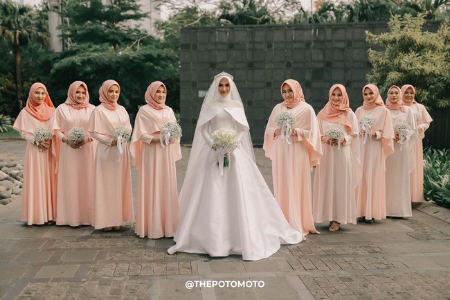 Saat resepsi di malam hari, Nada memilih gaun karya desainer ternama Hian Tjen. Gaun putih yang ia pakai memiliki detail bahu seperti gaun cinderella. Lagi-lagi, Nada memilih warna putih dengan potongan busana klasik. Foto: ThePhotoMoto