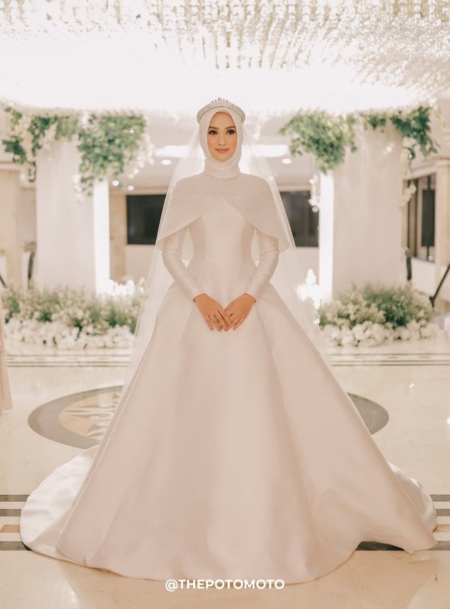 Untuk hijabnya, Nada memakai hijab segi empat dipadukan dengan veil. Veil tersebut bertabur payet yang senada dengan busana yang ia pakai. Ia memilih warna putih untuk momen sakralnya itu.  Foto: ThePhotoMoto
