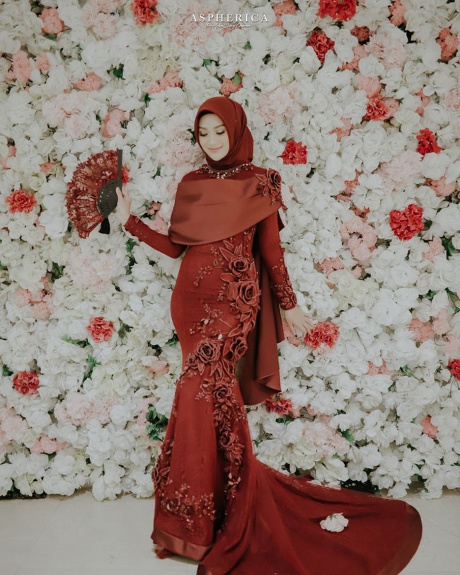 Di penghujung acara, Nada memakai busana karya Ayu Dyah Andari. Busana berwarna merah marun itu memiliki potongan mermaid dengan detail payet dan bordir yang kompleks. Nada juga memakai hijab berwarna merah marun, sehingga tampilannya malam itu terlihat glamor tapi tetap manis. Foto: Aspherica