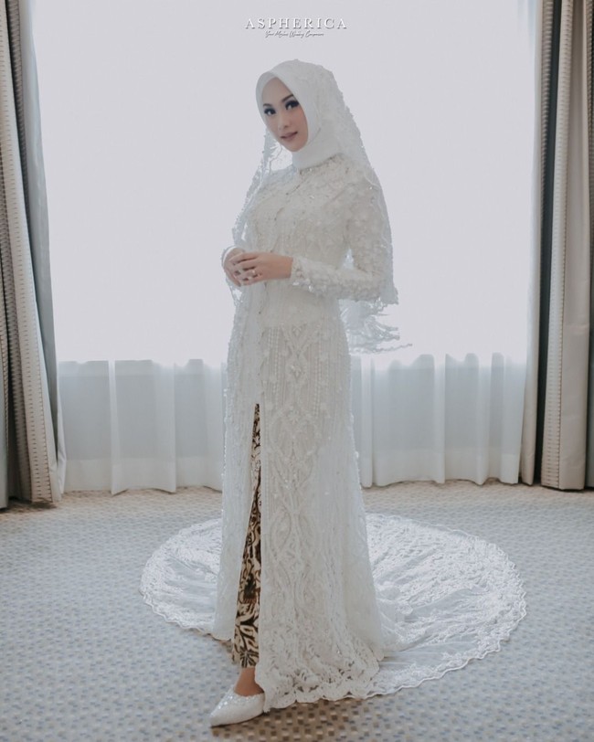 Saat akad nikah, ia memakai kebaya panjang menyerupai dress dipenuhi payet cantik. Busana karya Asky Febriyanti ini tampak cantik disandingkan dengan kain batik.  Foto: Aspherica
