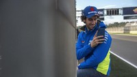Pebalap Suzuki, Alex Rins, menikmati suasan jelang test MotoGP Valencia di hari pertama. Dia asyik dengan gawainya untuk berfoto-foto. (Foto: Mirco Lazzari gp/Getty Images)
