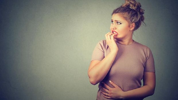 Closeup portrait nervous stressed young concerned woman biting fingernails looking anxiously craving something isolated gray background with copy space. Human emotion face expression feeling reaction
