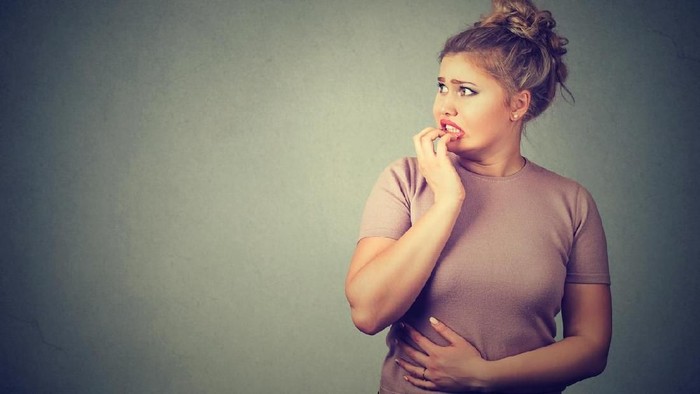 body shaming Closeup portrait nervous stressed young concerned woman biting fingernails looking anxiously craving something isolated gray background with copy space. Human emotion face expression feeling reaction
