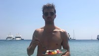 Menikmati waktu luang di Yunani, Andrew bersantai diantara deburan ombak sambil memakan salad buah yang segar. Foto: Instagram @drewtaggart