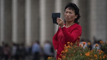 Ketika ada kejadian menarik, smartphone dengan sigap langsung digunakan buat memvideokan. Foto ini juga diambil di Pyongyang. (Foto: Ed JONES/AFP)
