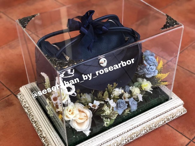 Salah satu kotak seserahan untuk Paula berisi tas Hermes seri Lindy berwarna biru navy. Terbuat dari calfskin, tas model boxy tersebut dijual seharga US$ 7.850 atau sekitar Rp 114 juta. Untuk seserahan, tas tersebut dipermanis dengan pita berwarna senada berikut rangkaian bunga tiruan yang meninggalkan kesan romantis. (Foto: Dok @seserahan_by_rosearbor)