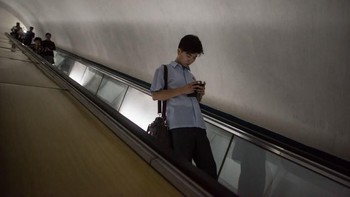 Negara Korut memang relatif tertutup, tapi tak berarti terbelakang. Seperti di negara-negara lain, sosok orang yang asyik sendiri dengan smartphone pun lazim di sana, seperti di stasiun kereta bawah tanah Pyongyang ini. (Foto: Ed JONES/AFP)