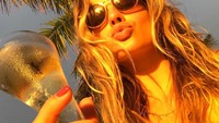 Berlibur dari rutinitas yang padat, Margot memamerkan pose imutnya saat menikmati segelas champagne dingin. Foto: Instagram @margotrobbie