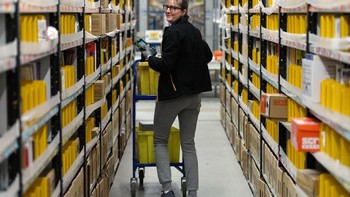 Para karyawan menuju ke rak-rak untuk mengambil pesanan yang dibeli konsumen Amazon. Foto: Getty Images