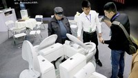 Seorang peserta pameran memperkenalkan tempat duduk toilet pintar dengan penutup sanitasi otomatis. Istimewa/Xinhuanet.