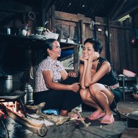 Baru-baru ini sosok HHen Nie kembali menjadi buah bibir karena unggahan fotonya di Instagram. Dia mengunggah kebersamannya dengan sang ibu di rumah mereka yang begitu sederhana. Tampak rumah HHen Nie terbuat dari kayu yang pada beberapa bagian sudah tampak menghitam. Area dapur rumahnya belum ada sentuhan modernitas. Miss Universe Vietnam 2017 itu pun tampak berjongkok di dekat ibunya yang duduk di atas jengkok (tempat duduk kecil). Foto: Dok. Instagram HHen Nie