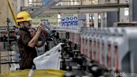 Seorang pekerja melakukan pengecekan tempat minyak pelumas oli agar tak ada yang rusak atau cacat produksi.
